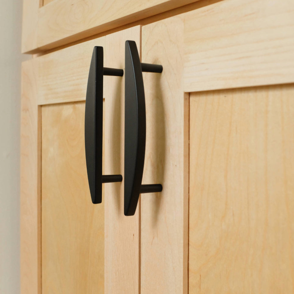 two black half moon cabinet pulls installed on light wooden cabinet