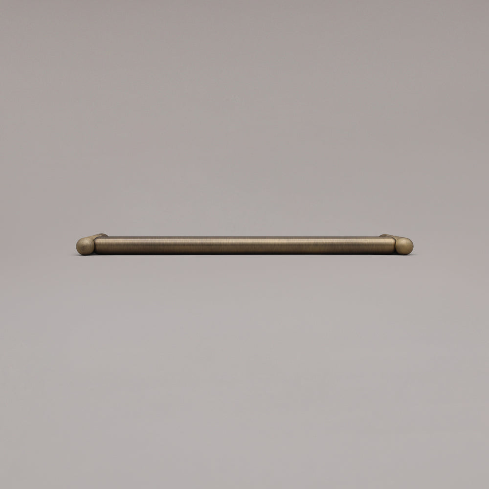 12" Knurled appliance pull in Aged Brass laying on gray background