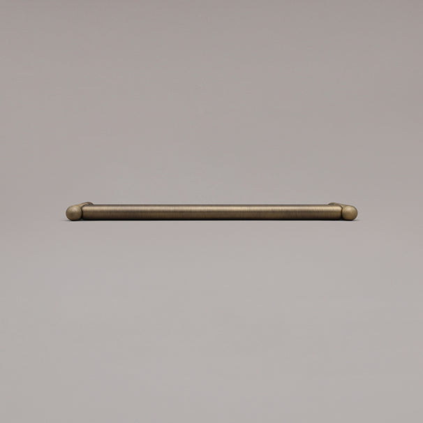 12" Knurled appliance pull in Aged Brass laying on gray background