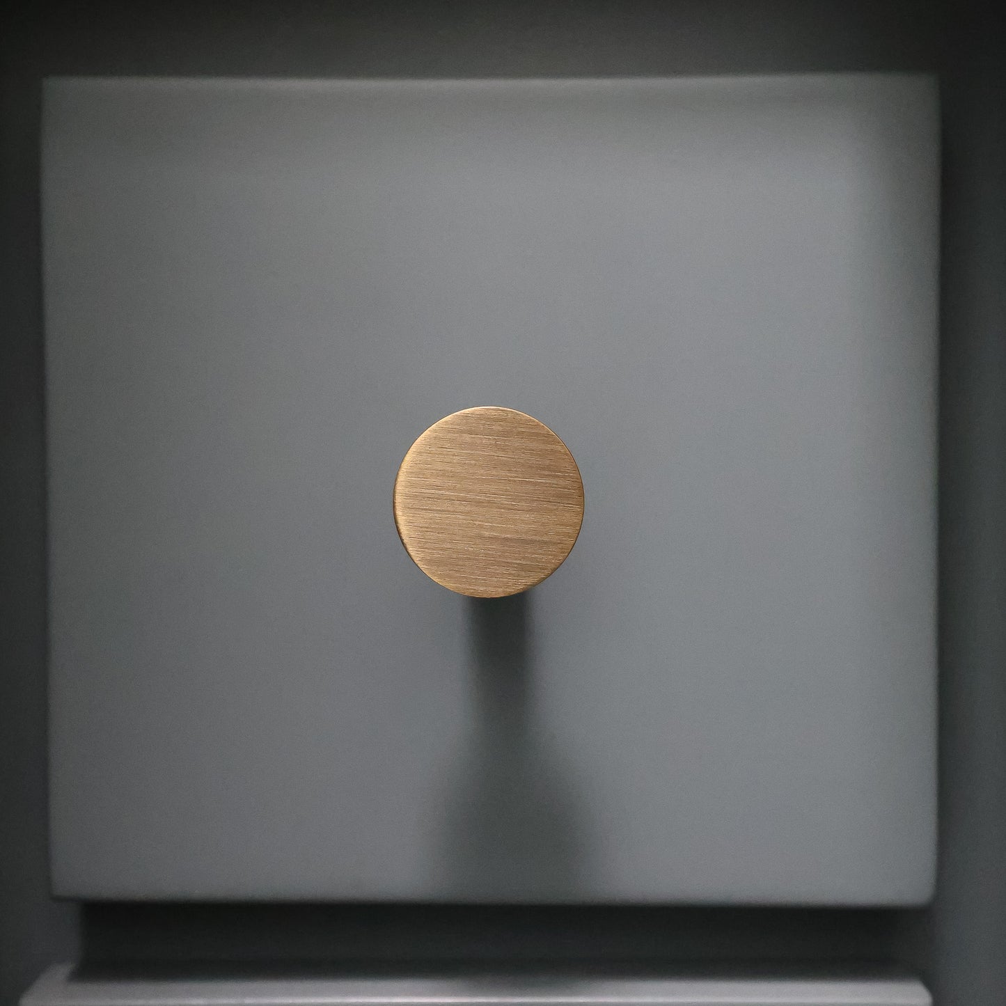 Aged brass knob on a blue surface front facing view.