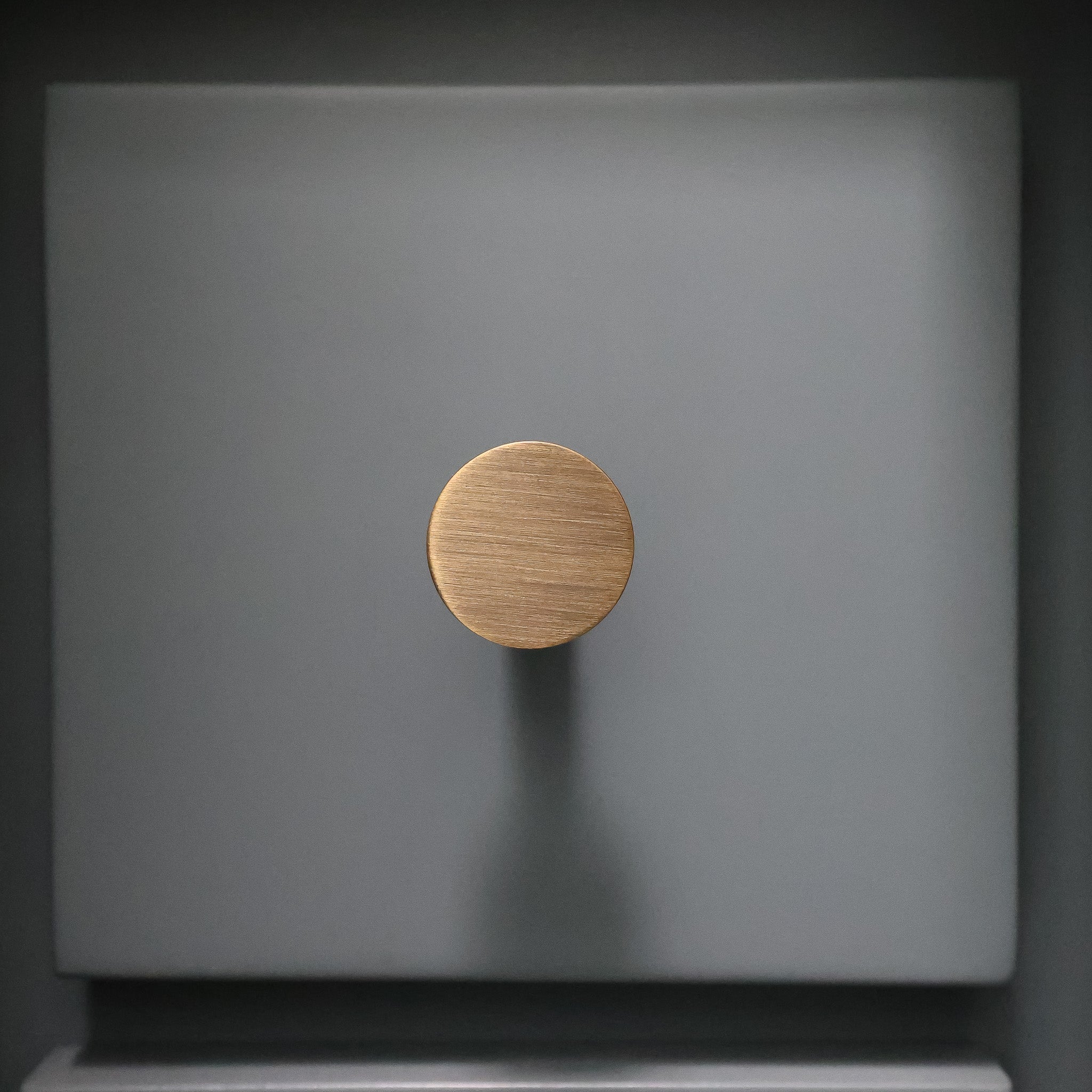 Aged brass knob on a blue surface front facing view.