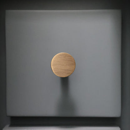 Aged brass knob on a blue surface front facing view.