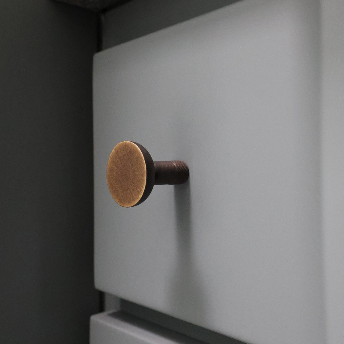 Skinny Knurled Cabinet Knob in Antique English Finish on a Blue Bathroom Drawer.