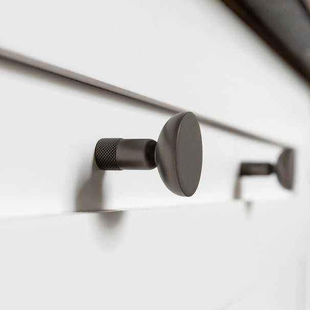 Skinny cabinet knob on a white shaker kitchen drawer.