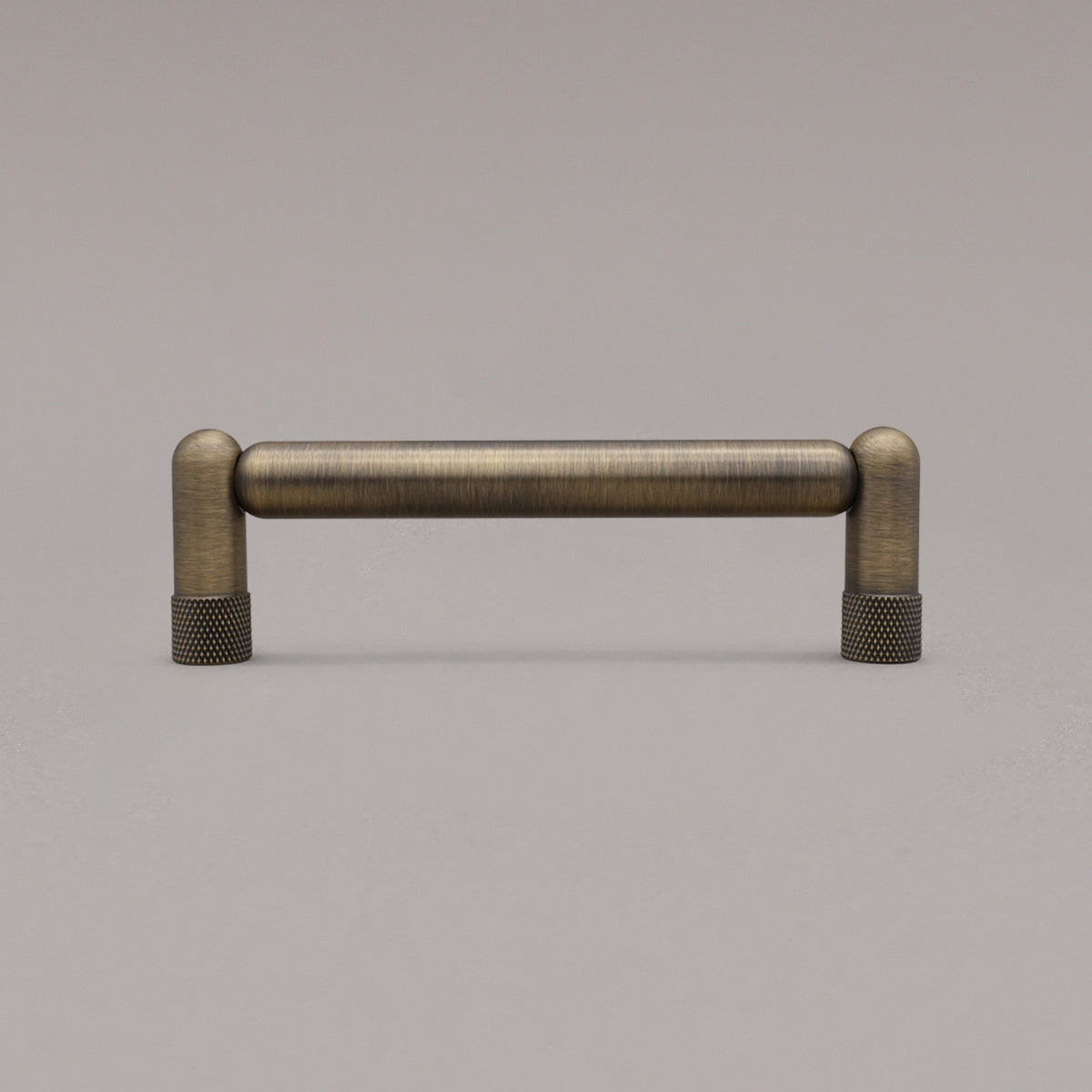 standing knurled aged brass cabinet pull on gray background
