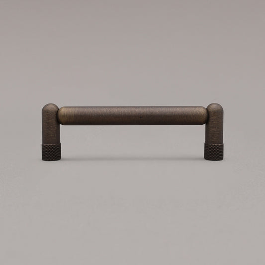 standing knurled aged brass cabinet pull on gray background