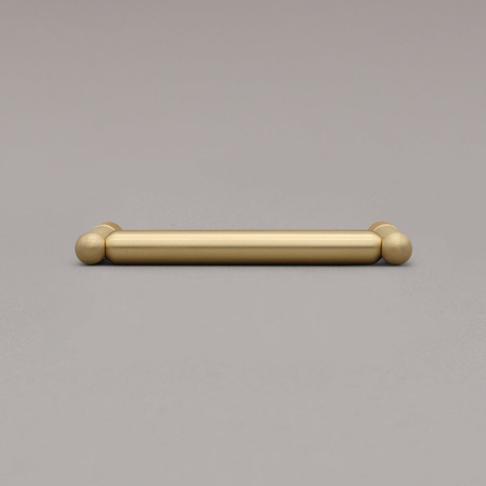 knurled satin brass gold cabinet pull laying on gray background