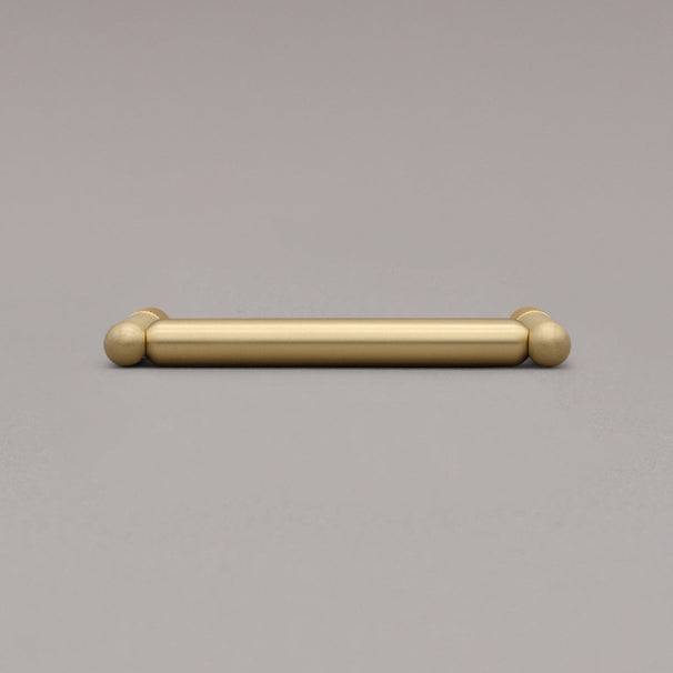 knurled satin brass gold cabinet pull laying on gray background