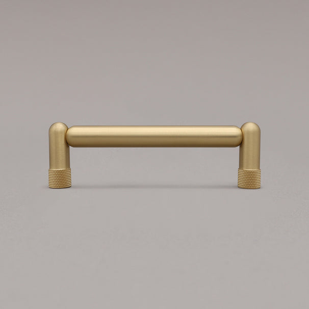 standing knurled satin brass gold cabinet pull on gray background