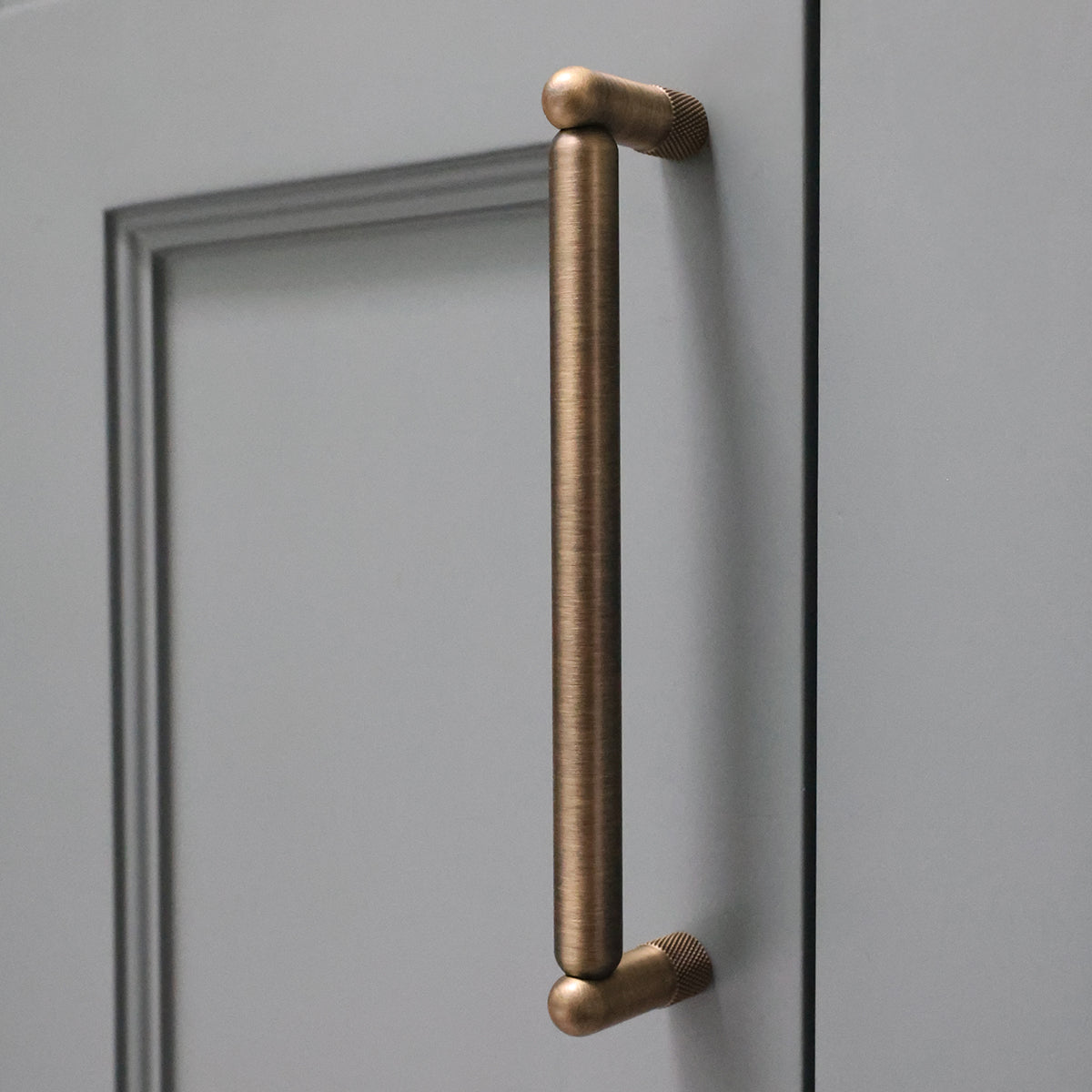 Aged brass cabinet handle on a blue door.