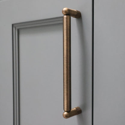Aged brass cabinet handle on a blue door.
