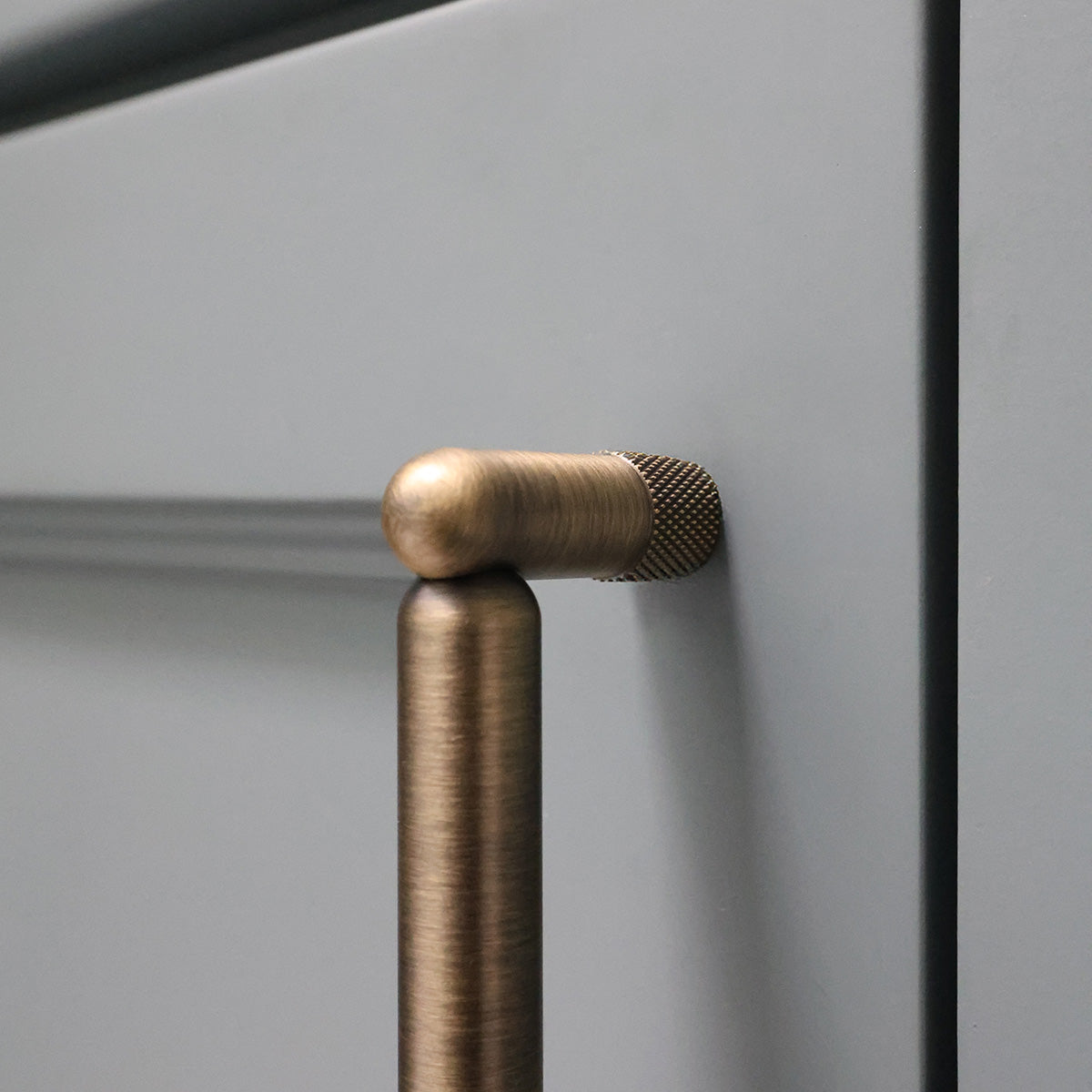 Aged brass stem of cabinet pull on bathroom vanity.