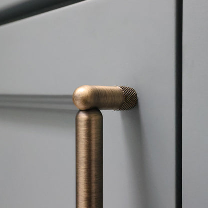 Aged brass stem of cabinet pull on bathroom vanity.