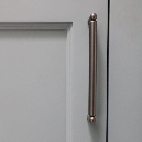 graphite knurled cabinet pull installed on blue bathroom cabinet door