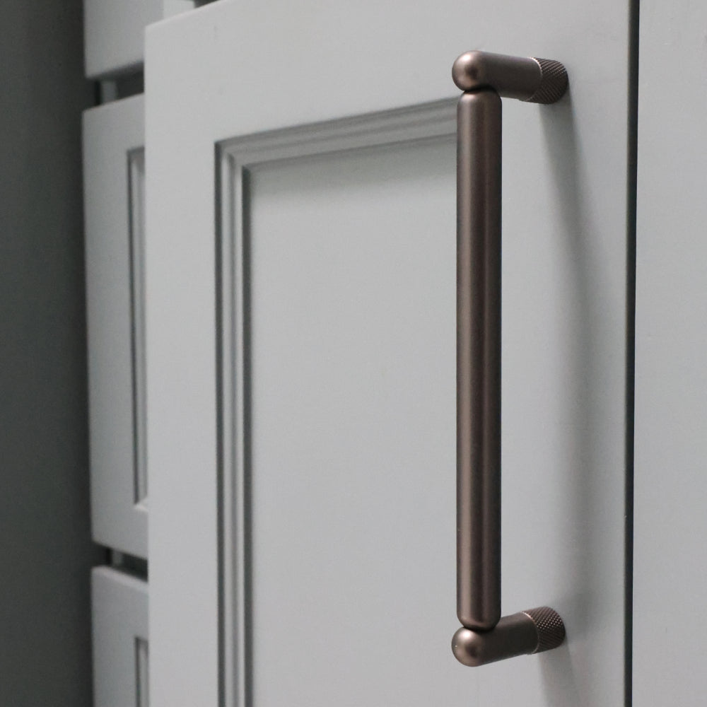 graphite knurled cabinet pull installed on blue bathroom cabinet door