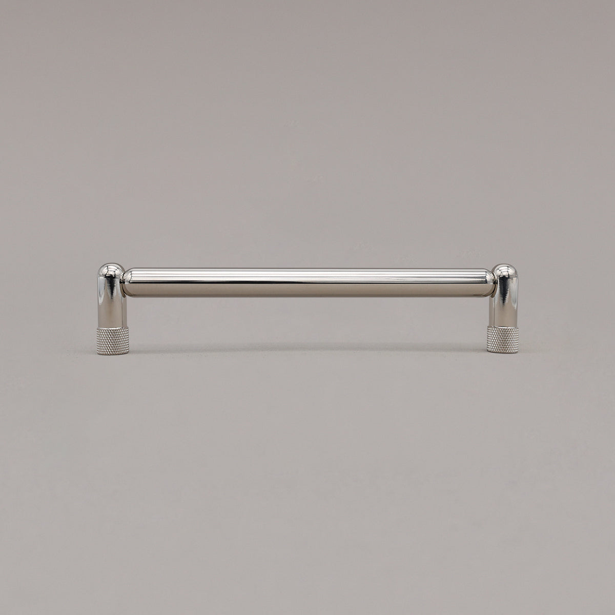 Medium polished nickel knurled cabinet pull standing on gray background
