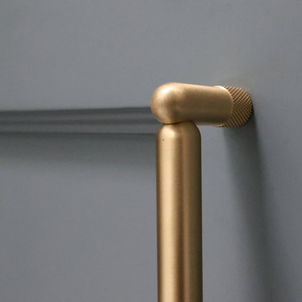 Close up of satin brass knurled pull installed on blue bathroom cabinet door