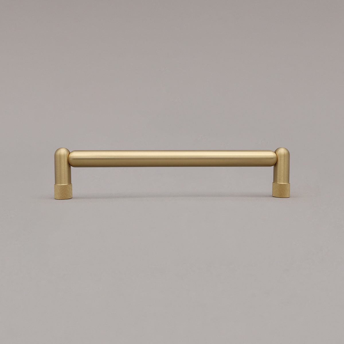 Medium satin brass gold knurled cabinet pull standing on gray background