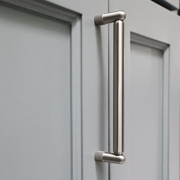 Knurled cabinet knob in satin nickel installed on blue bathroom cabinet door