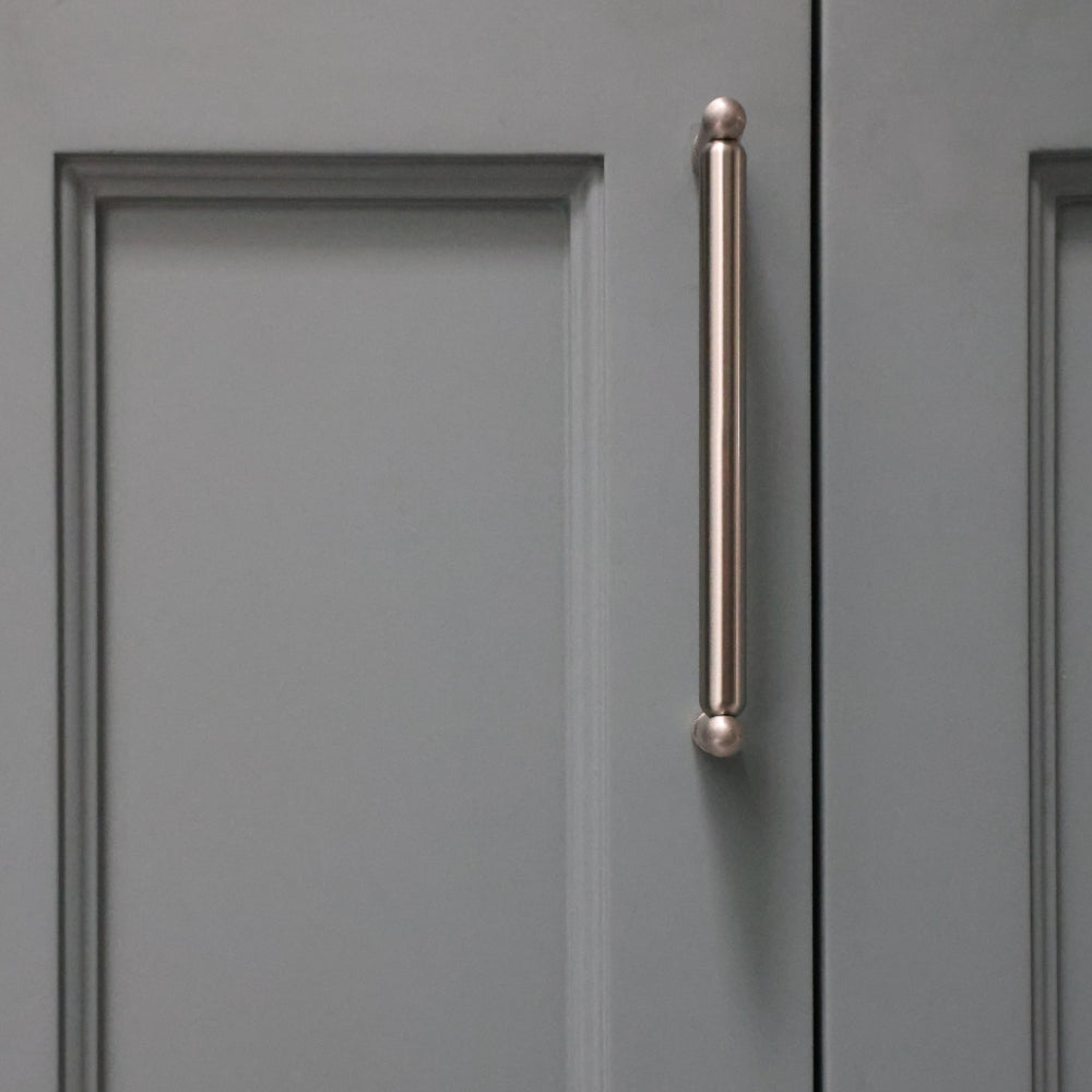 Knurled cabinet knob in satin nickel installed on blue bathroom cabinet door