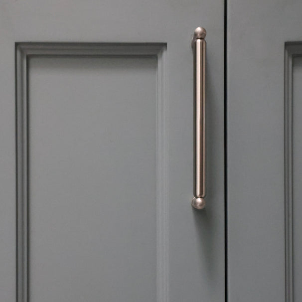Knurled cabinet knob in satin nickel installed on blue bathroom cabinet door
