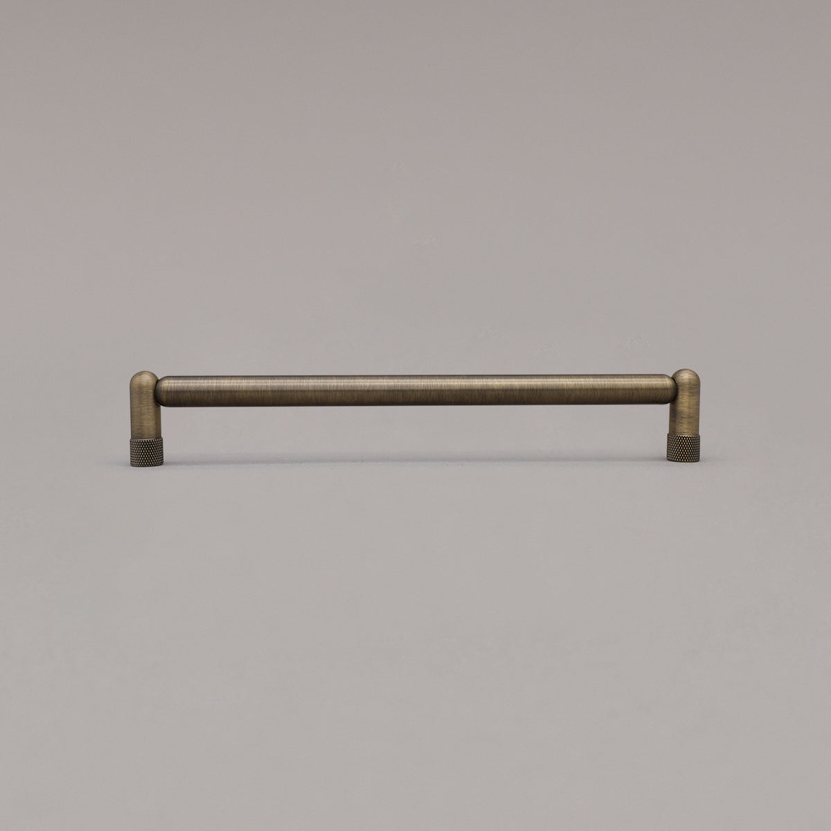 Large aged brass knurled cabinet pull standing on gray background