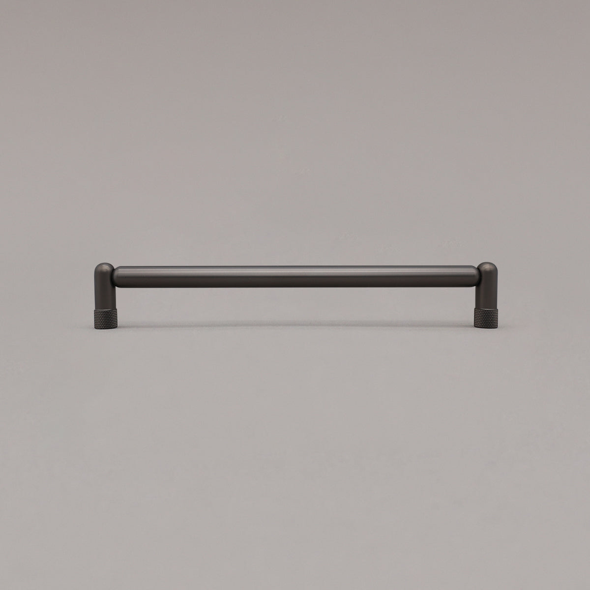 Large graphite gray knurled cabinet pull standing on gray background