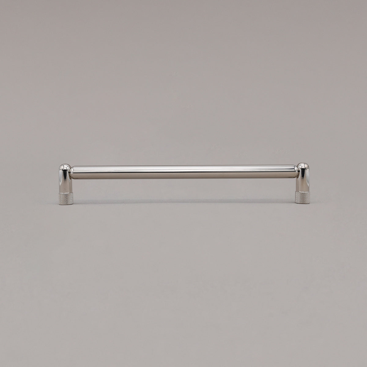 Large polished nickel knurled cabinet pull standing on gray background