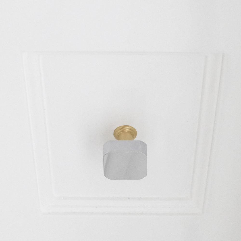 Polished chrome and satin brass gold two tone square knob installed on white bathroom drawer