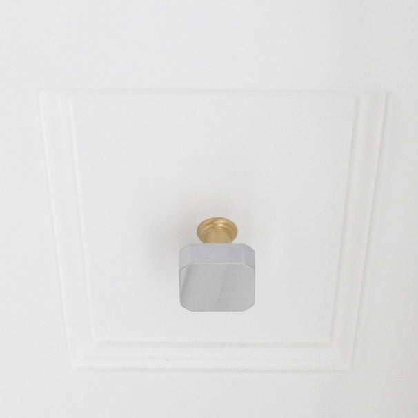 Polished chrome and satin brass gold two tone square knob installed on white bathroom drawer