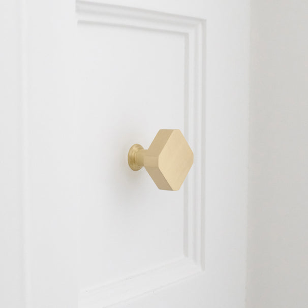 Satin brass gold square knob installed on white bathroom cabinet drawer