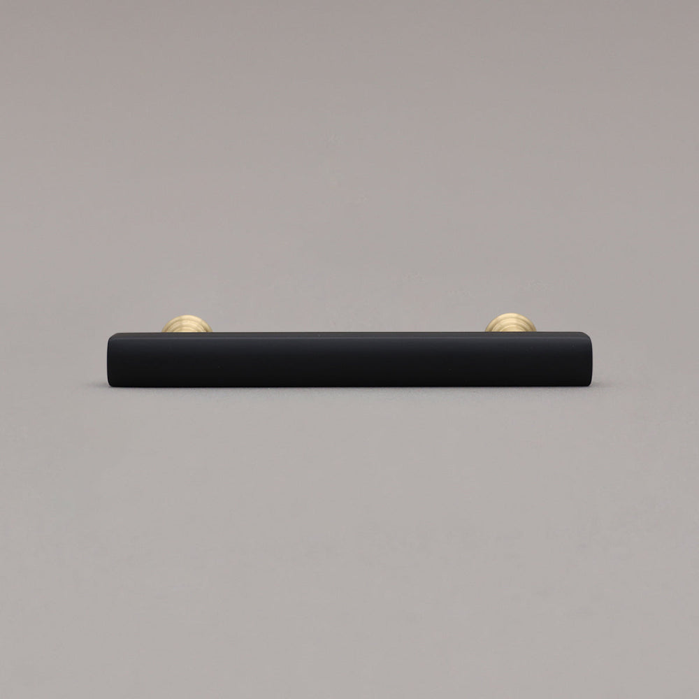 mod black and brass pull laying down on gray background