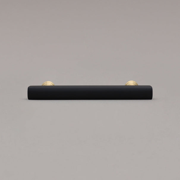 mod black and brass pull laying down on gray background