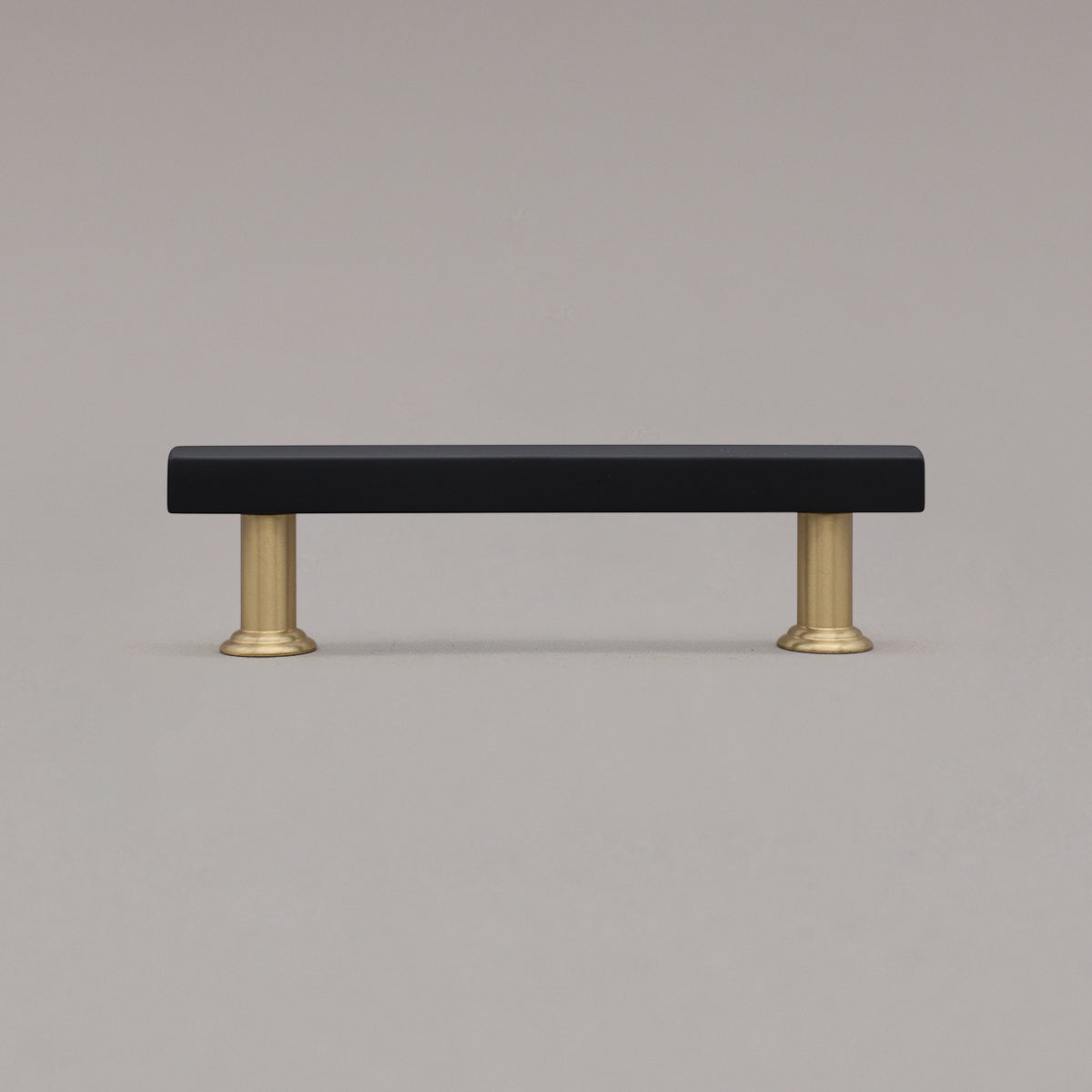 black and satin brass mod cabinet pull standing on gray background