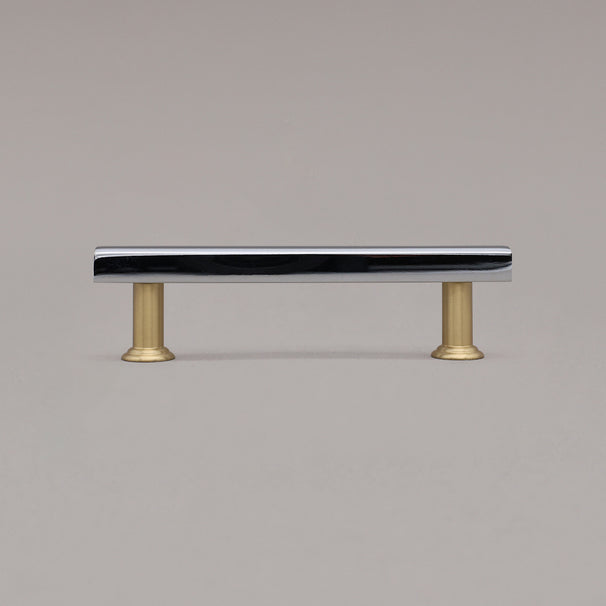 small chrome and satin brass mod cabinet pull standing on gray background