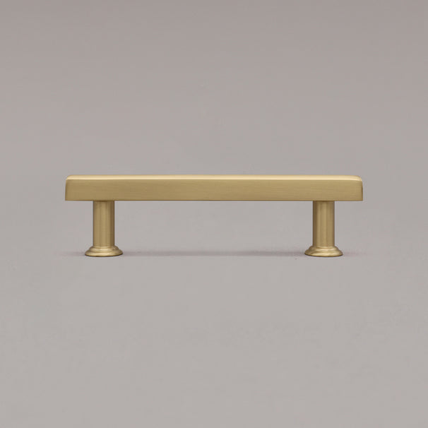small satin brass mod cabinet pull standing on gray background