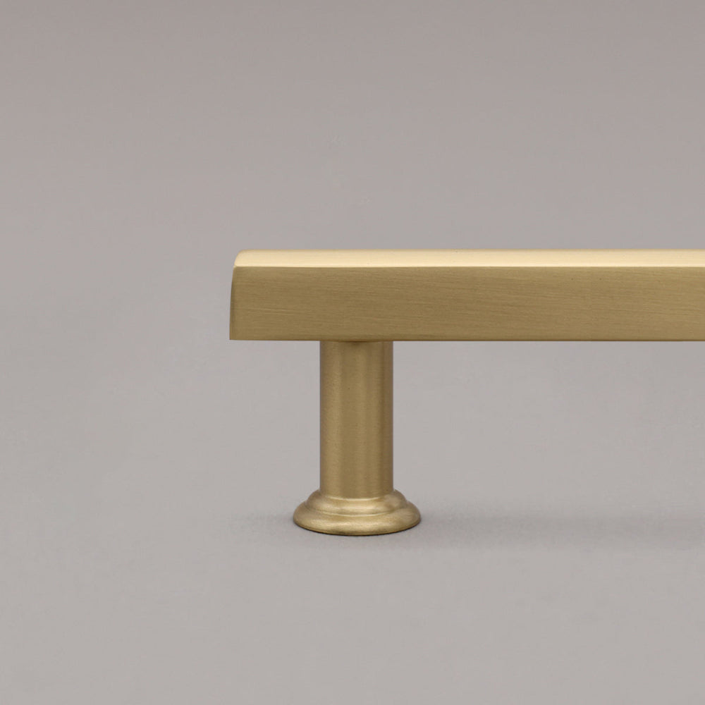 satin brass gold mod cabinet pull close up on stem on gray background