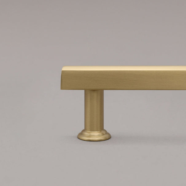 satin brass gold mod cabinet pull close up on stem on gray background