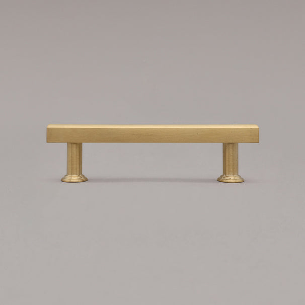 small unlacquered satin brass mod cabinet pull standing on gray background