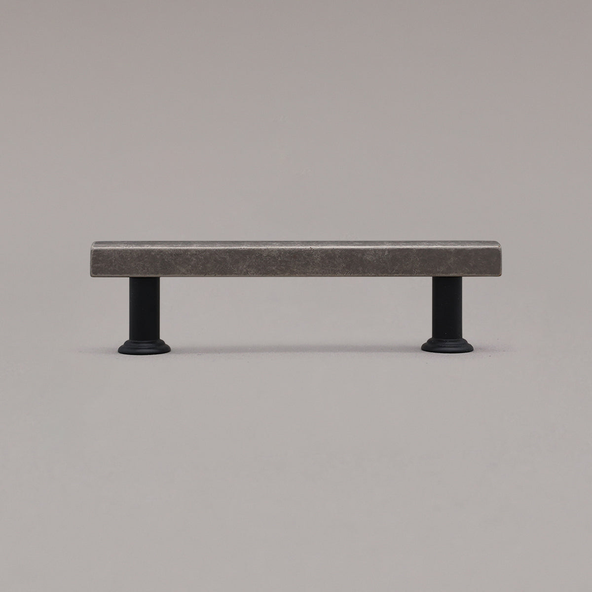weathered nickel and black mod cabinet pull standing on gray background