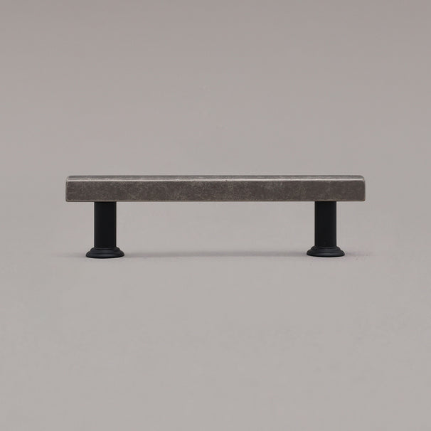 small weathered nickel and black mod cabinet pull standing on gray background