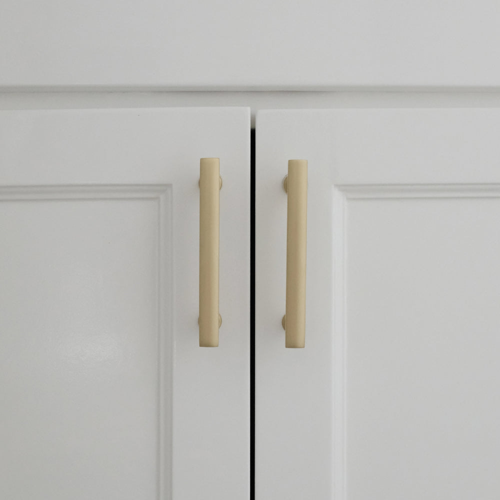 white satin brass cabinet pulls installed on white background