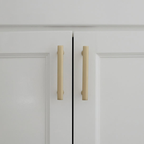 white satin brass cabinet pulls installed on white background