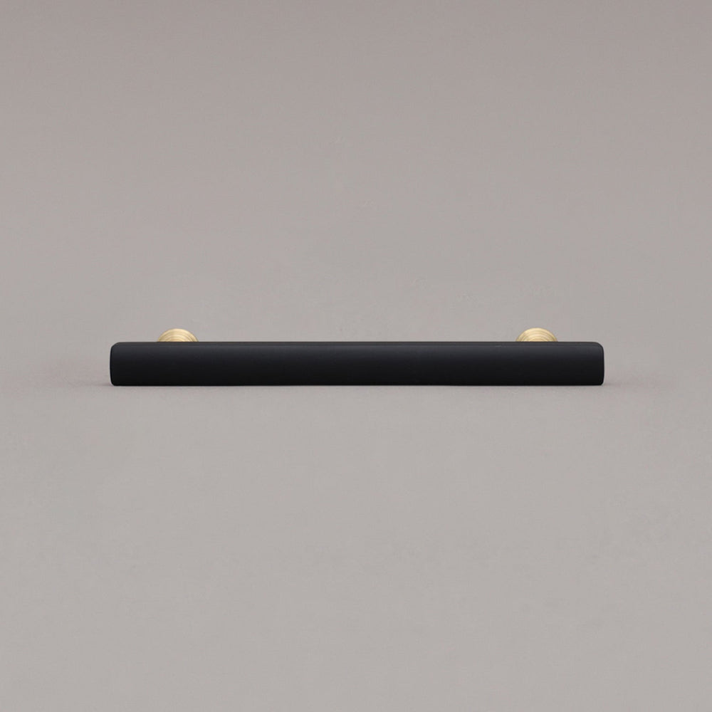 medium matte black and satin brass pull front view on gray background