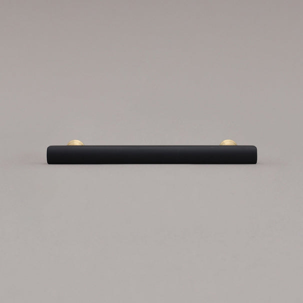 medium matte black and satin brass pull front view on gray background