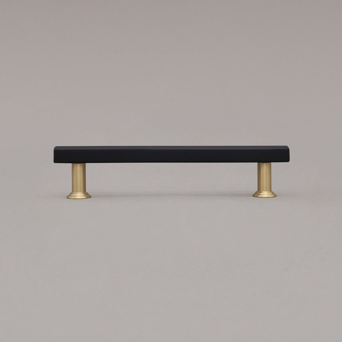 medium black and satin brass mod cabinet pull standing on gray background