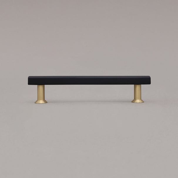 medium black and satin brass mod cabinet pull standing on gray background