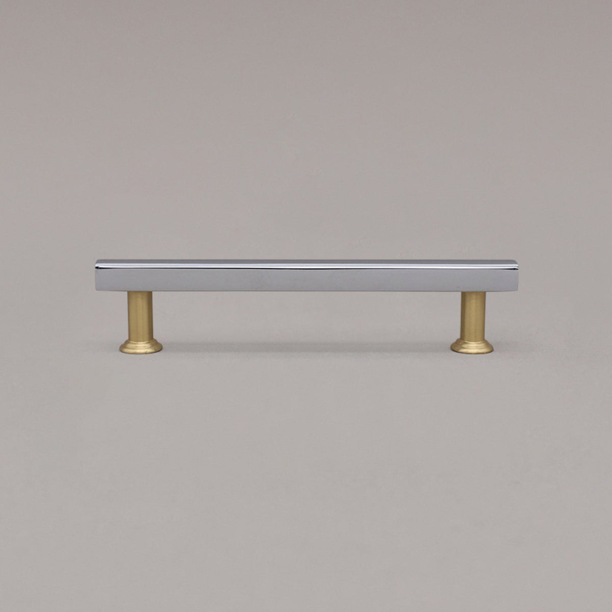 medium chrome and satin brass mod cabinet pull standing on gray background