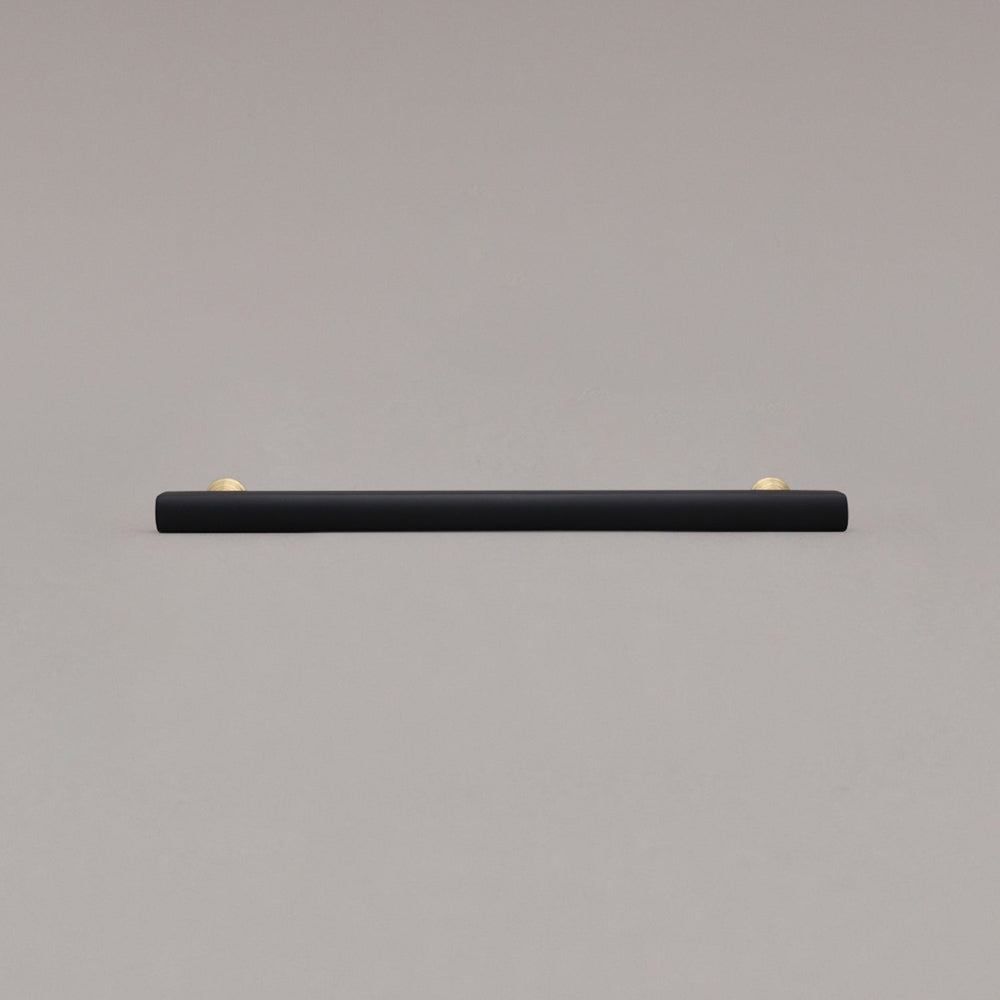 large matte black and satin brass pull front view on gray background