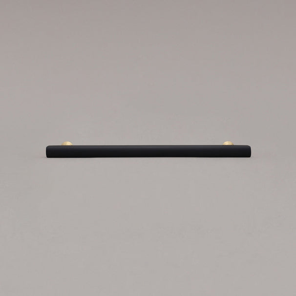 large matte black and satin brass pull front view on gray background